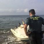 Un agente de la Guardia Civil frente a una patera-taxi que llegó al litoral de Carboneras (Almería)