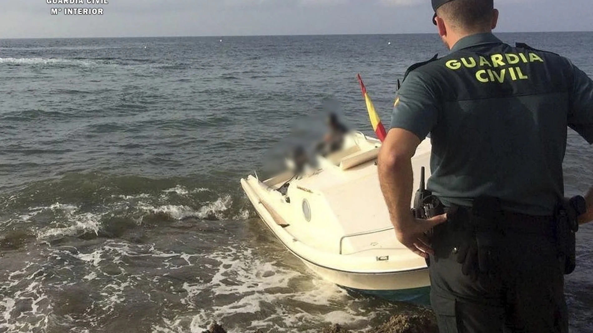 Un agente de la Guardia Civil frente a una patera-taxi que llegó al litoral de Carboneras (Almería)