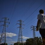 Un joven pasa junto a unas torres de alta tensión en la ciudad de Madrid.