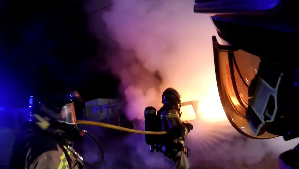 Varios bomberos apagan el todoterreno Land Rover incendiado, utilizado el lunes en el intento de fuga de un preso, tras recibir el aviso a las 00:20 de la noche entre el lunes y el martes