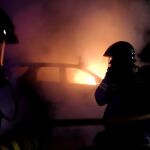 Varios bomberos apagan el todoterreno Land Rover incendiado, utilizado el lunes en el intento de fuga de un preso, tras recibir el aviso a las 00:20 de la noche entre el lunes y el martes