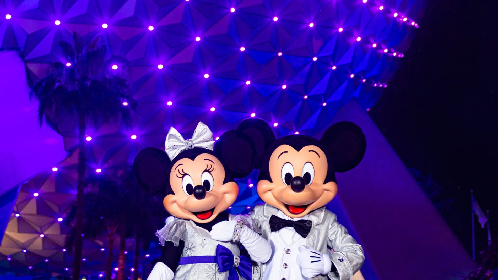 PUSA9787. LAKE BUENA VISTA (FL, EEUU), 16/10/2023.- Fotografía cedida por Disney donde aparecen Mickey y Minnie Mouse con sus deslumbrantes trajes platino con ocasión de los 100 años de Disney mientras posan en la entrada del parque temático de EPCOT en Lake Buena Vista, Florida (EE. UU). De un pequeño estudio familiar de animación para niños a un multimillonario conglomerado mediático internacional: Disney cumple 100 años repartiendo magia a los más pequeños y asentada, según algunos experto...