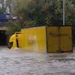 Un repartidor de Correos intenta cruzar una zona inundada con el camión en Madrid