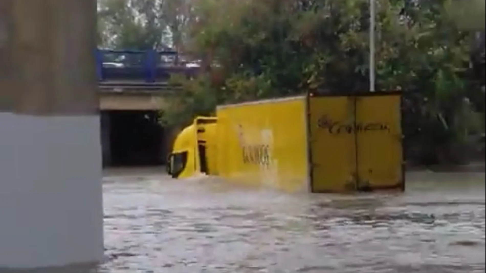 Un repartidor de Correos intenta cruzar una zona inundada con el camión en Madrid