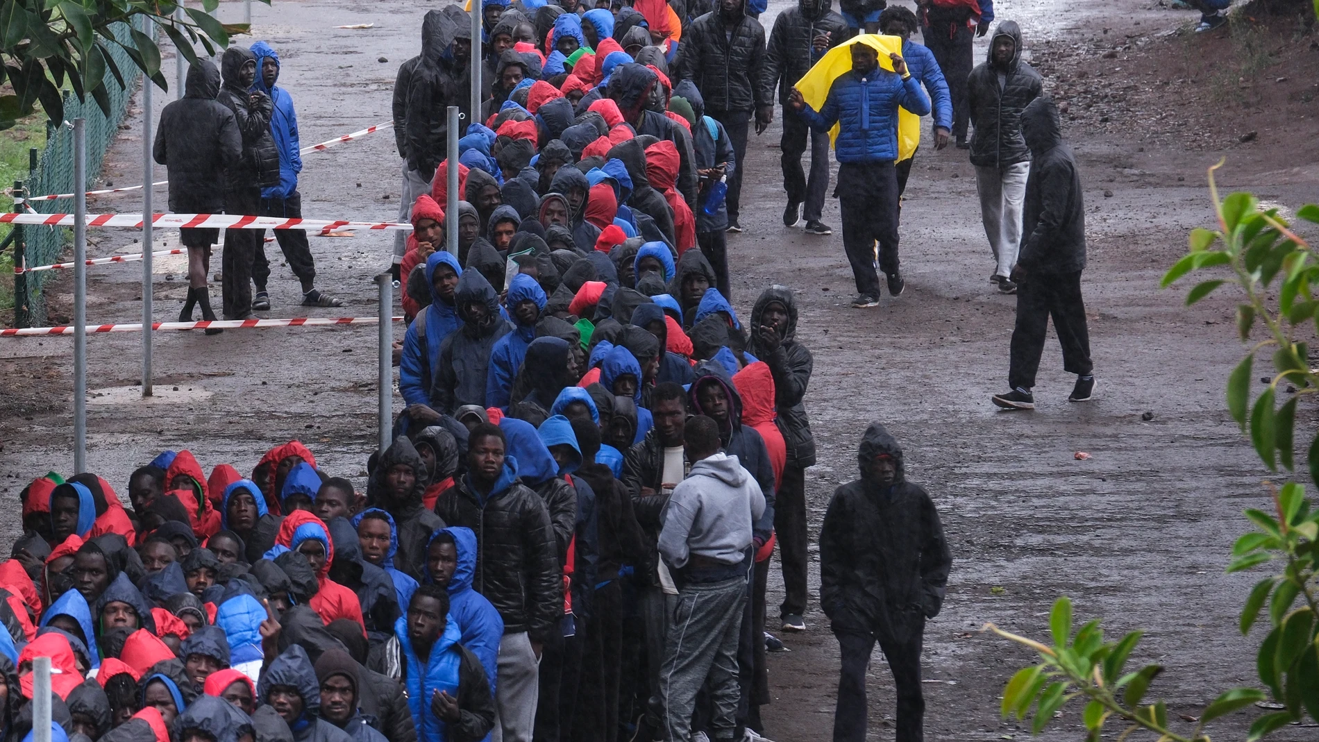 LA LAGUNA (TENERIFE), 22/10/2023.- Cientos de migrantes de origen subsahariano, en su mayoría senegaleses, hacen fila bajo la lluvia este domingo para acceder al centro de acogida para migrantes de Las Raíces en Tenerife. El diputado senegalés Guy Marius Sagna, del partido opositor que lidera Ousmane Sonko, visita el campamento de acogida de inmigrantes de Las Raíces, donde están alojados buena parte de los nacionales de ese país que han llegado en cayuco a las islas en los últimos días. EFE/...