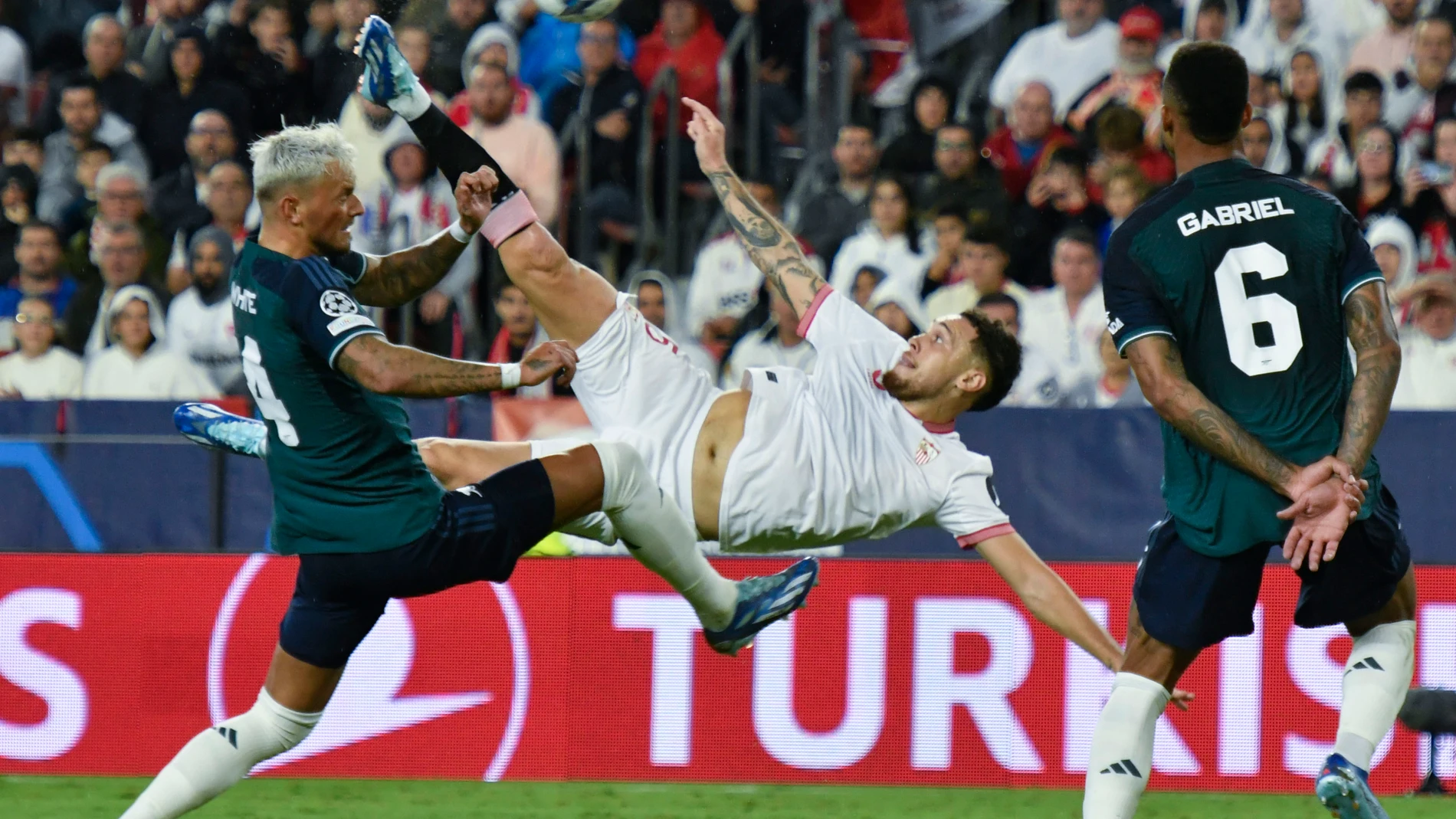 Sevilla, 24/10/2023.- El centrocampista argentino del Sevilla, Lucas Ocampos (c), intenta rematar ante el defensa del Arsenal, Ben White, durante el encuentro correspondiente a la fase de grupos de la Liga de Campeones que disputan hoy martes en el estadio Sánchez Pizjuán de Sevilla. EFE/Raul Caro.