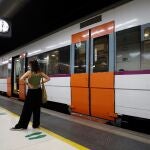 Una mujer espera ante un tren parado de Rodalies