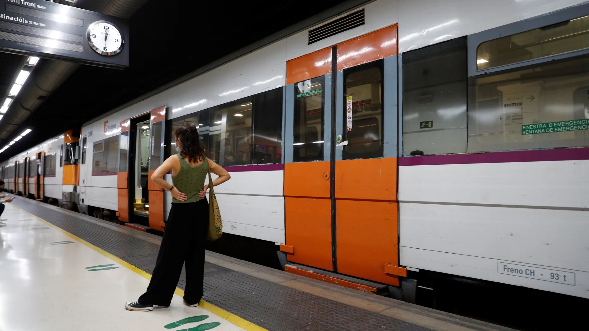 Una mujer espera ante un tren parado de Rodalies