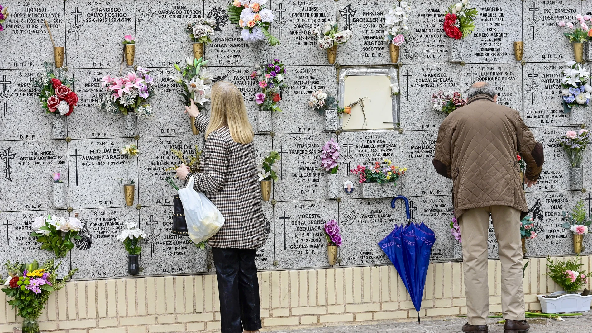 Personas limpian y colocan flores en el cementerio de la Almudena en Madrid.- EFE/ Víctor Lerena