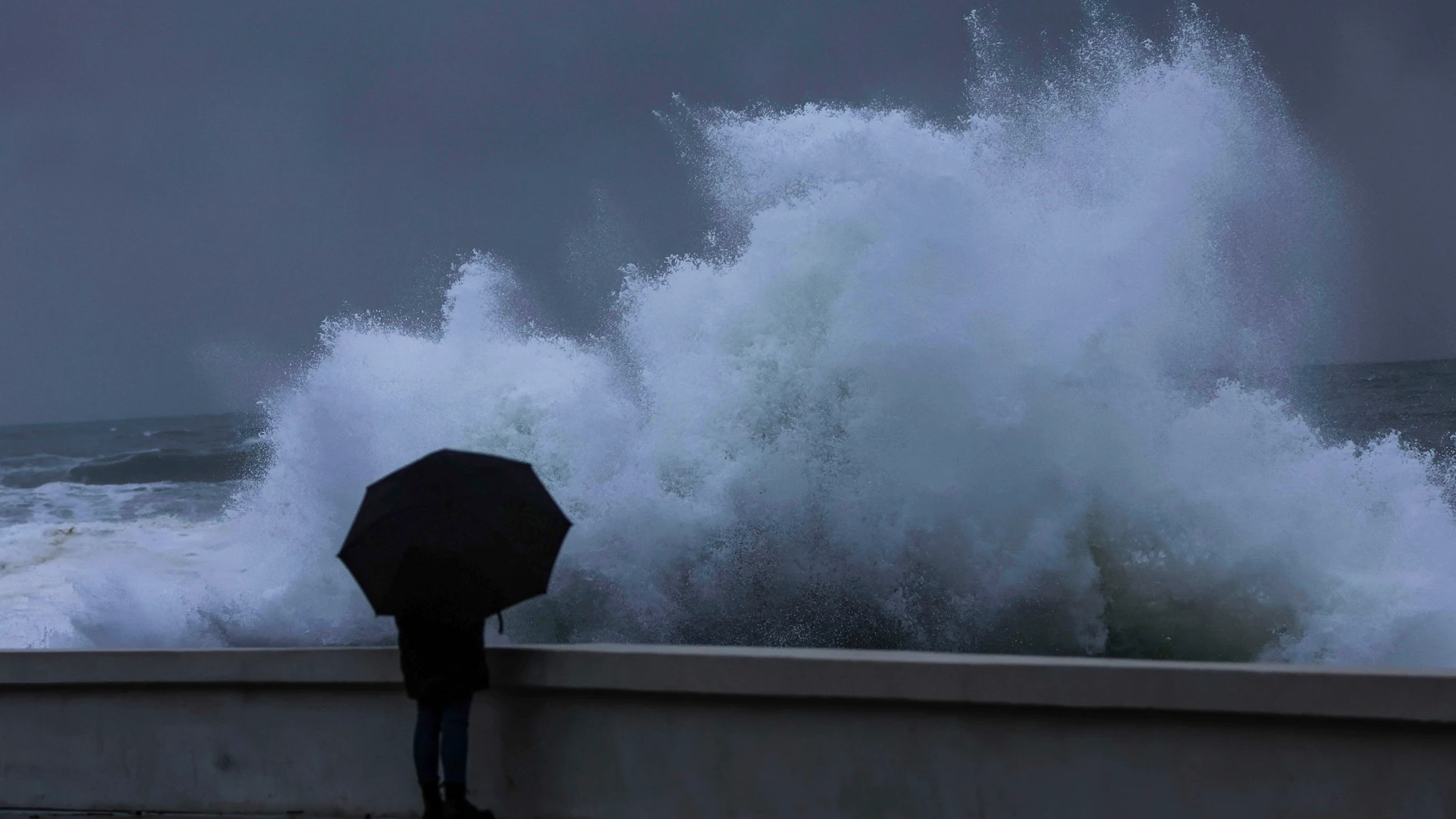 Una persona observa como rompe el fuerte oleaje en la costa de Baiona