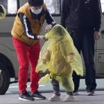 Una mujer intenta proteger de la covid a un niño con un impermeable en Wuhan en abril de 2020
