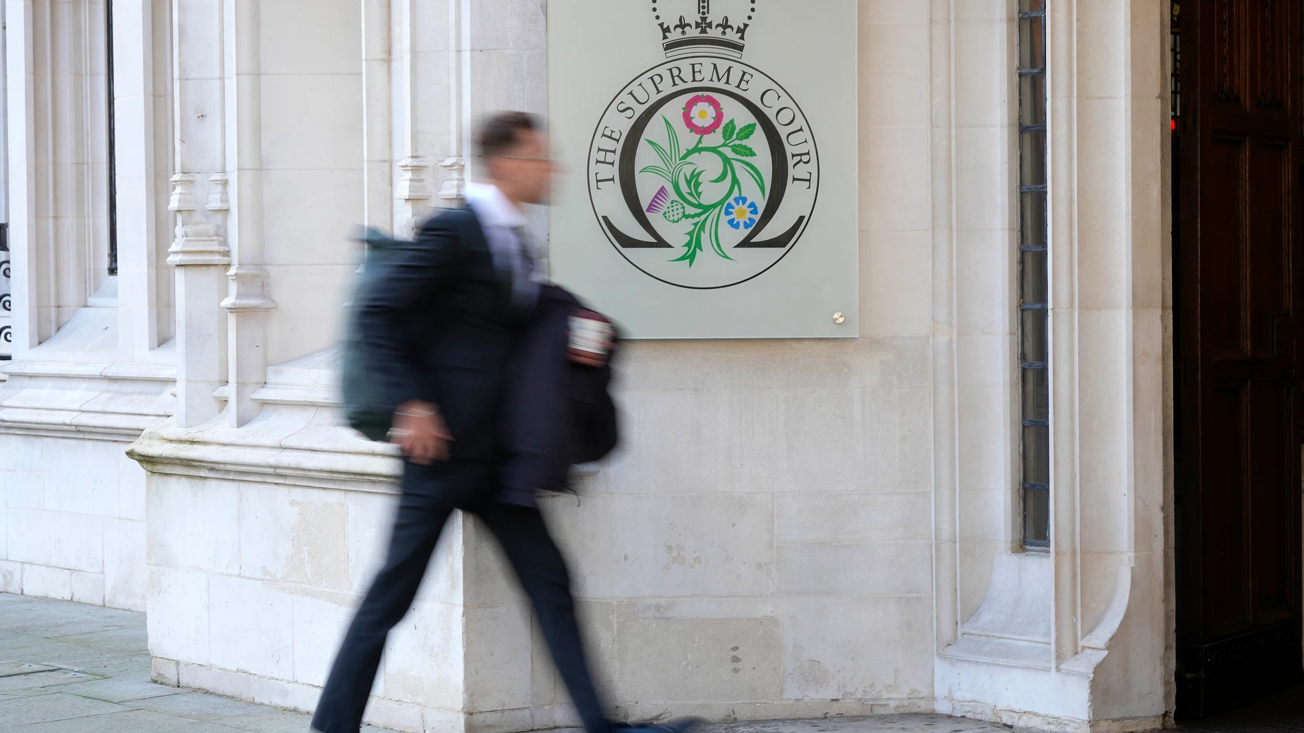 A man walks into the Supreme Court in London, Wednesday, Nov. 15, 2023. Britain's highest court is set to rule Wednesday, Nov. 15 on whether the government's plan to send asylum-seekers to Rwanda is legal, delivering a boost or a blow to a contentious central policy of Prime Minister Rishi Sunak's administration. Five justices on the U.K. Supreme Court will deliver judgment in the government's attempt to overturn a lower court ruling that blocked deportations. (AP Photo/Kirsty Wigglesworth)