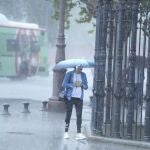 Una mujer se resguarda de la lluvia bajo un paragüas