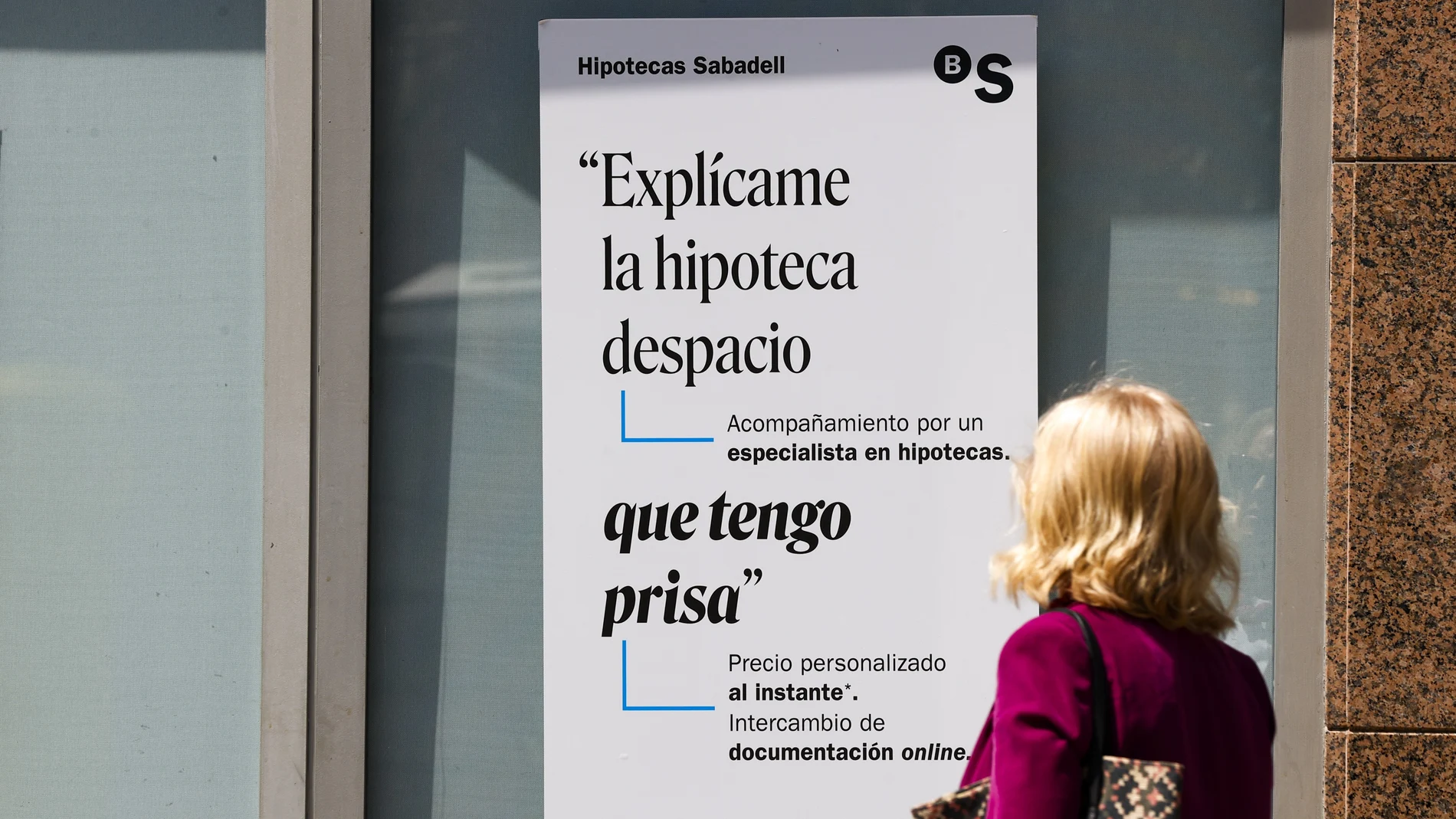 Una mujer ante un cartel bancario sobre las hipotecas.