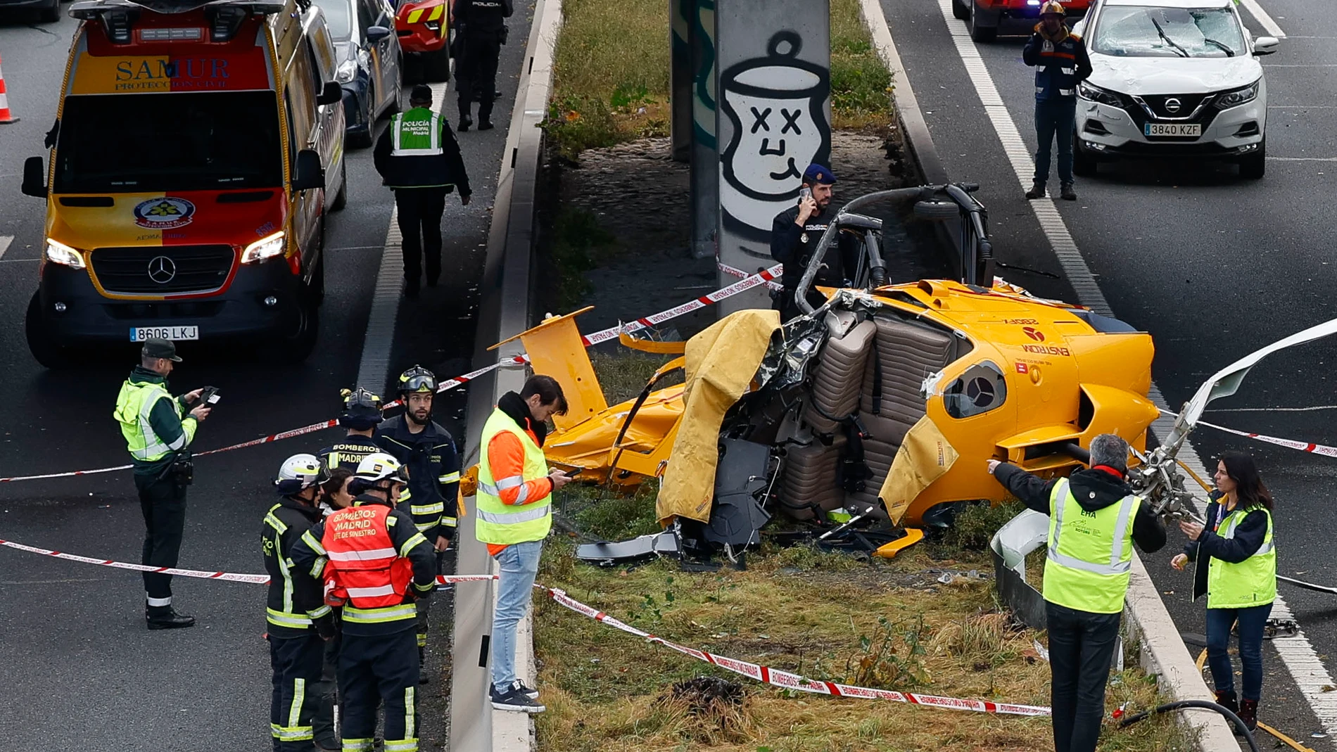 MADRID, 01/12/2023.- Miembros de los servicios de Emergencia se personan este viernes en la carretera M-40 de Madrid donde un helicóptero con dos personas a bordo ha caído y ha provocado un traumatismo craneoencefálico leve a uno de los ocupantes y una posible fractura de fémur al otro, mientras que un conductor que circulaba por la vía ha sufrido cortes muy leves por cristales. EFE/JJ Guillén