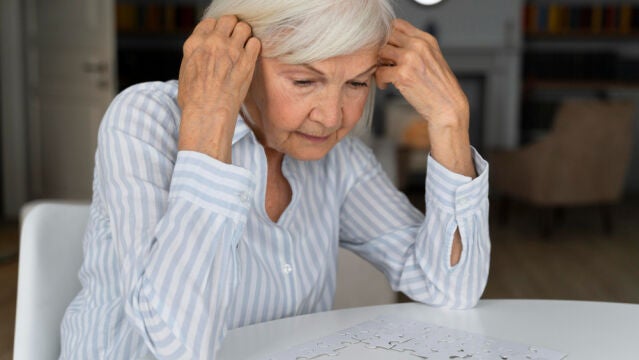 Una mujer anciana hace un puzle