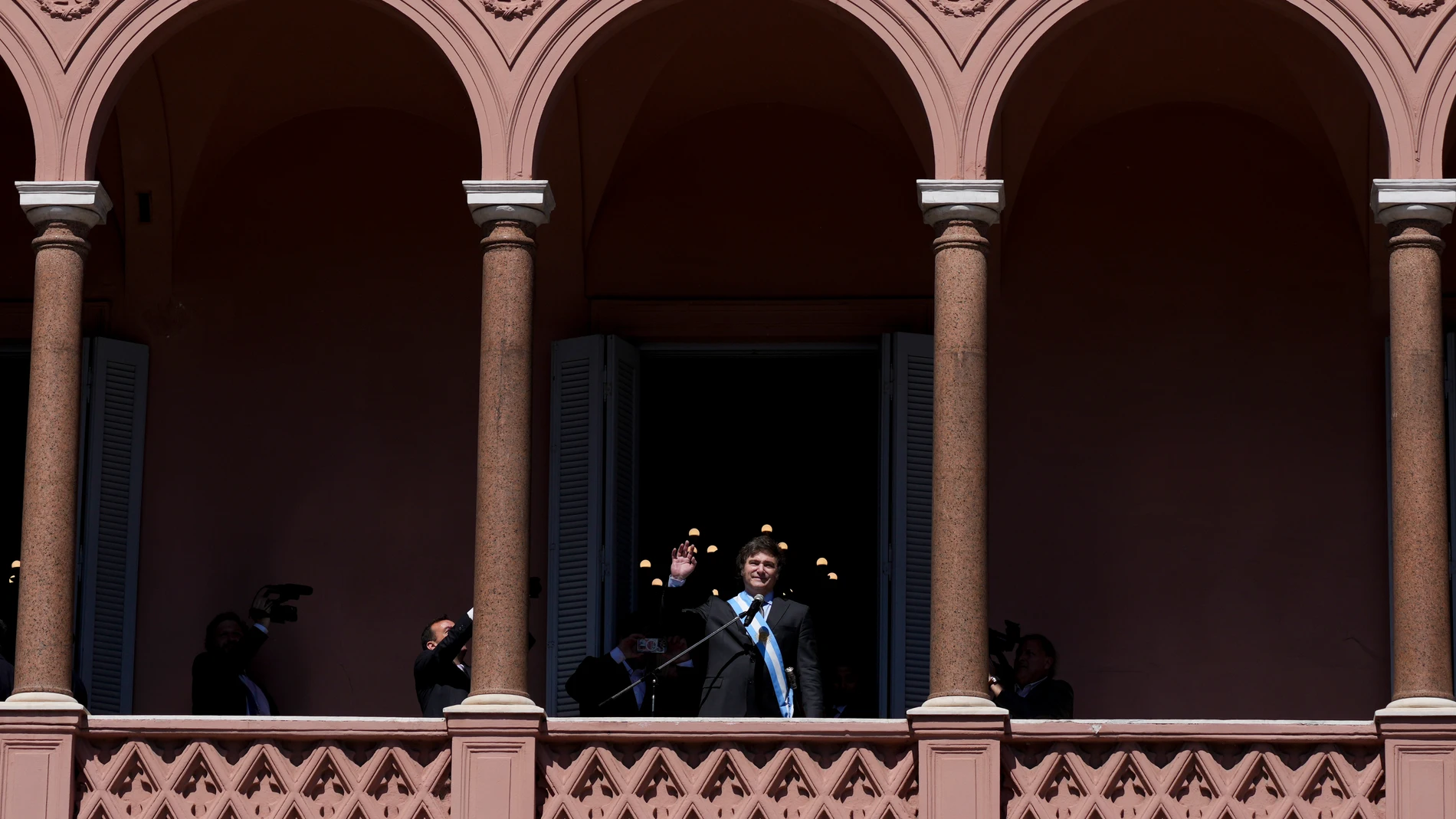 FILE- Argentina's newly sworn-in President Javier Milei waves to supporters from the balcony of the government house in Buenos Aires, Argentina, Dec. 10, 2023. Milei has drastically cut spending to end the fiscal deficit and contain inflation of almost 161% annually, including devaluing the peso more than 50%, dismissing public employees, suspending public works and reducing transportation and energy subsidies. (AP Photo/Matilde Campodonico, File)
