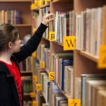 Estudiante consulta una biblioteca de libros de papel