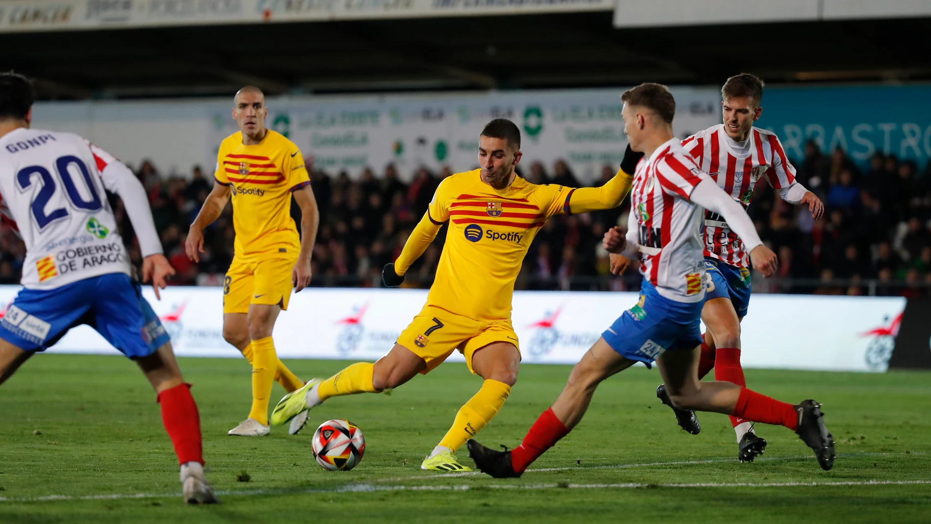 BARBASTRO (HUESCA), 07/01/2024.- El delantero del FC Barcelona, Ferrán Torres (i), golpea el balón ante los defensores del Barbastro durante el encuentro correspondiente a los dieciseisavos de final de la Copa del Rey disputado hoy domingo en el Estadio Municipal de la localidad oscense. EFE / Javier Cebollada.