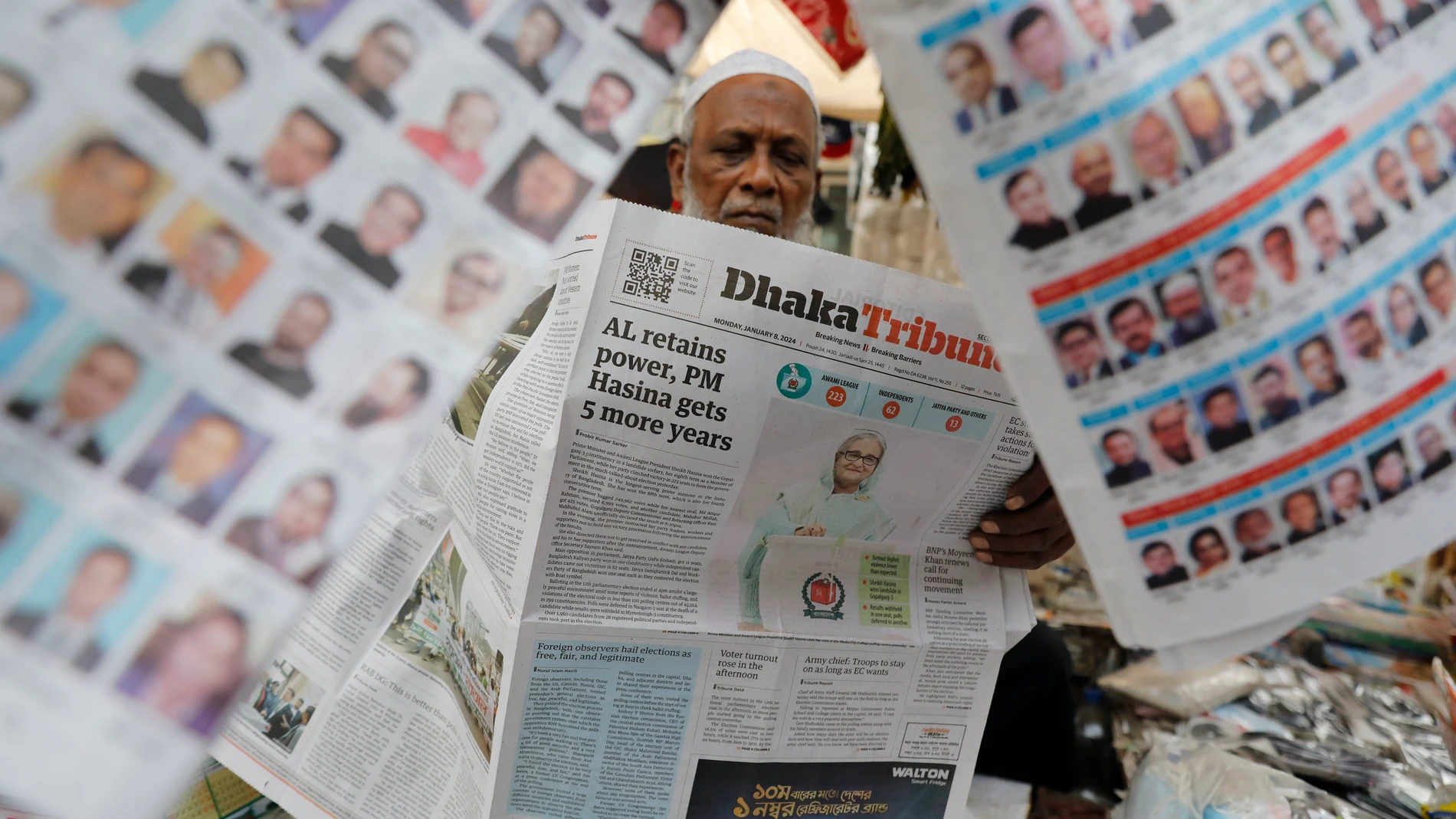 A man reads a Bangladeshi newspaper that has the news of Prime Minister Sheikh Hasina's election victory in Dhaka, Bangladesh, Monday, Jan.8, 2024. Hasina has won an overwhelming majority in Bangladesh's parliamentary election after a campaign fraught with violence and a boycott from the main opposition party, giving her and her Awami League a fourth consecutive term. (AP Photo/Mahmud Hossain Opu)