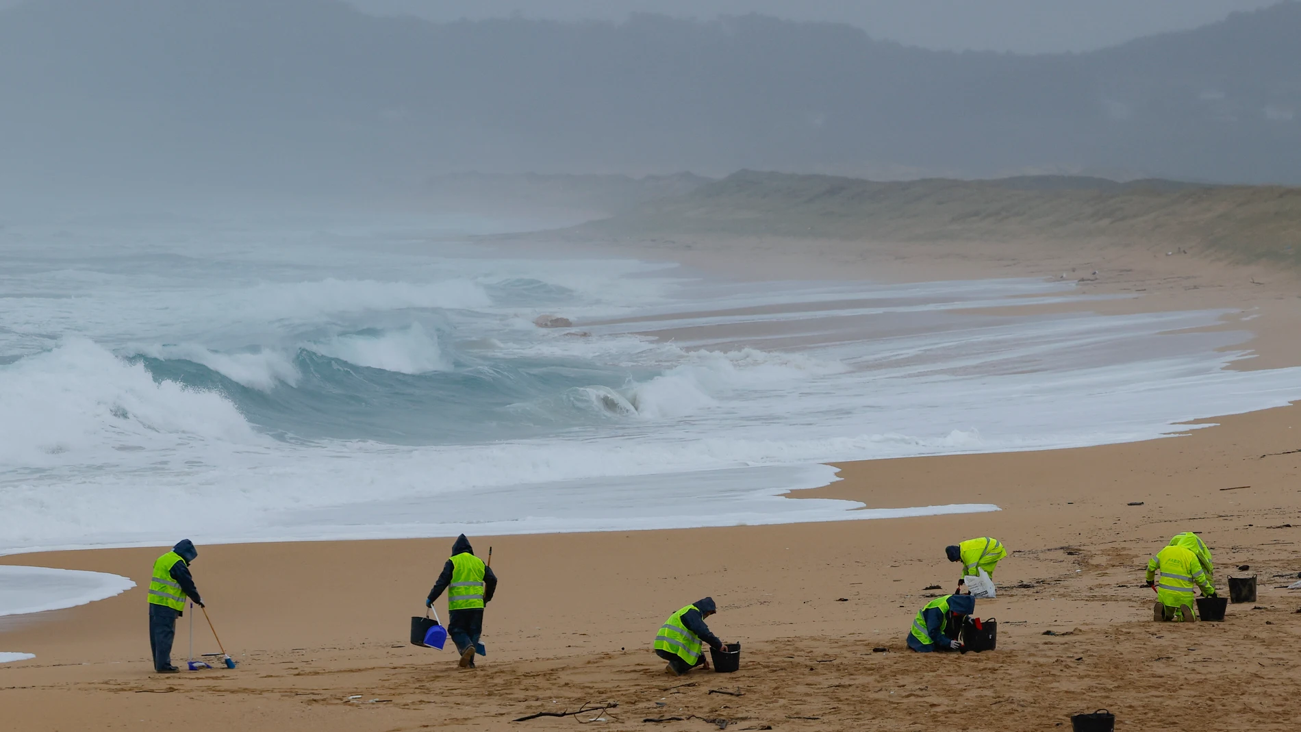 RIBEIRA (A CORUÑA), 09/01/2024.- Operarios de empresas contratadas por la Xunta retiran los pellets o bolitas para fabricar plástico que aparecen en las playas gallegas y de Asturias, tras la caída de un contenedor de un barco el pasado diciembre, esta mañana en la playa de O Vilar, en el parque natural de Corrubedo, A Coruña. EFE/Lavandeira jr