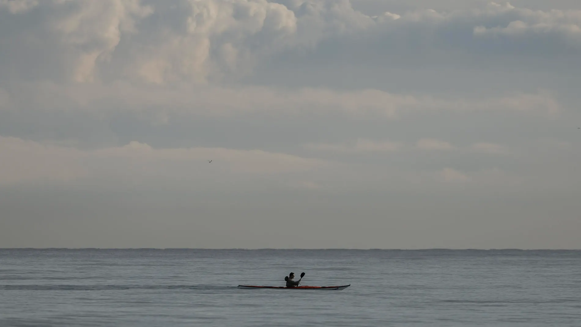 Una persona en la playa de la Malvarrosa hoy, con el cielo nuboso de fondo.