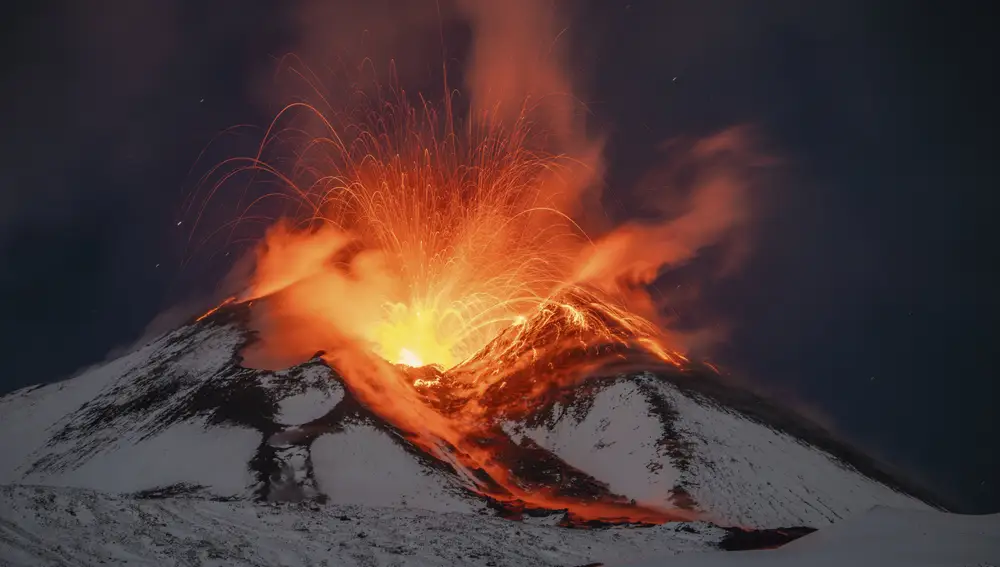 Lava erupts from snow-covered Mt Etna volcano, Sicily, Italy, early Saturday, Nov. 25, 2023. Europe's most active volcano remains active scattering ashes around a vastly populated area on its slopes. (AP Photo/Etnawalk, Giuseppe Di Stefano)