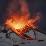 Lava erupts from snow-covered Mt Etna volcano, Sicily, Italy, early Saturday, Nov. 25, 2023. Europe's most active volcano remains active scattering ashes around a vastly populated area on its slopes. (AP Photo/Etnawalk, Giuseppe Di Stefano)