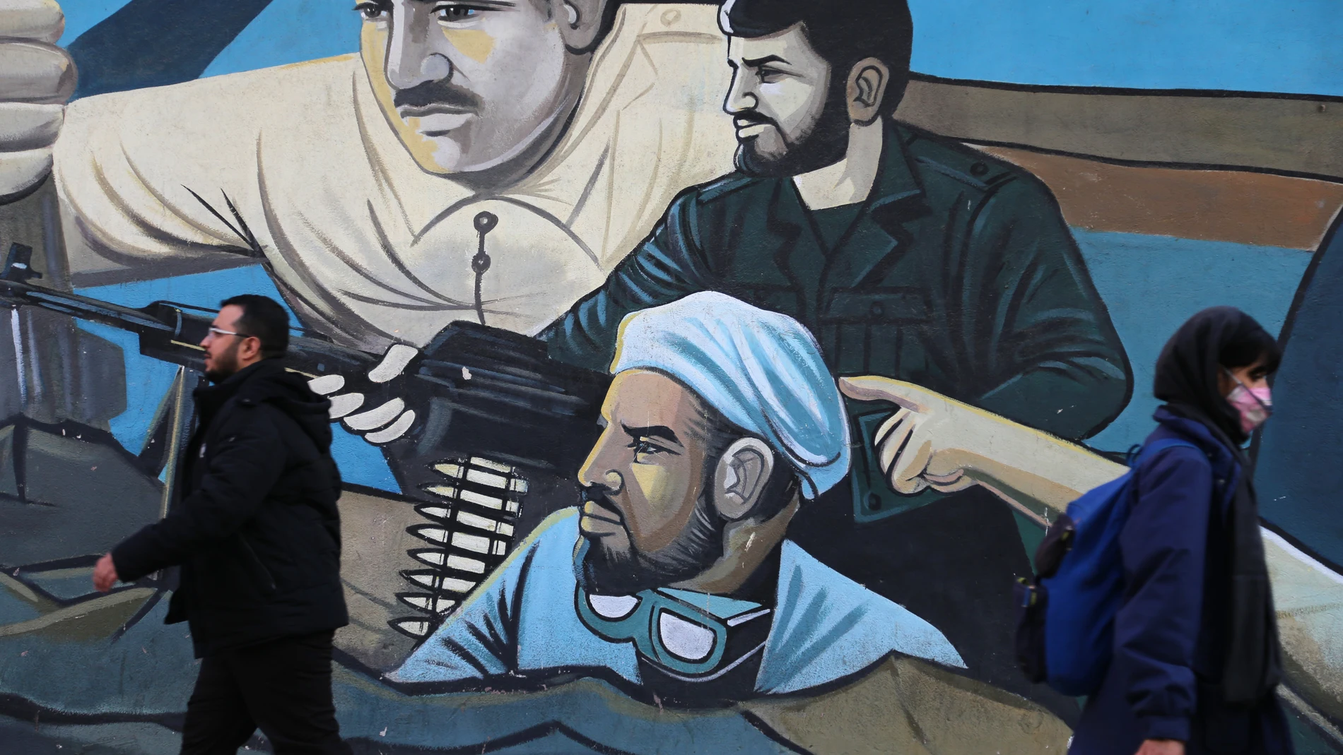 January 17, 2024, Tehran, Iran: An Iranian man and woman walk past a mural in downtown Tehran. 17/01/2024