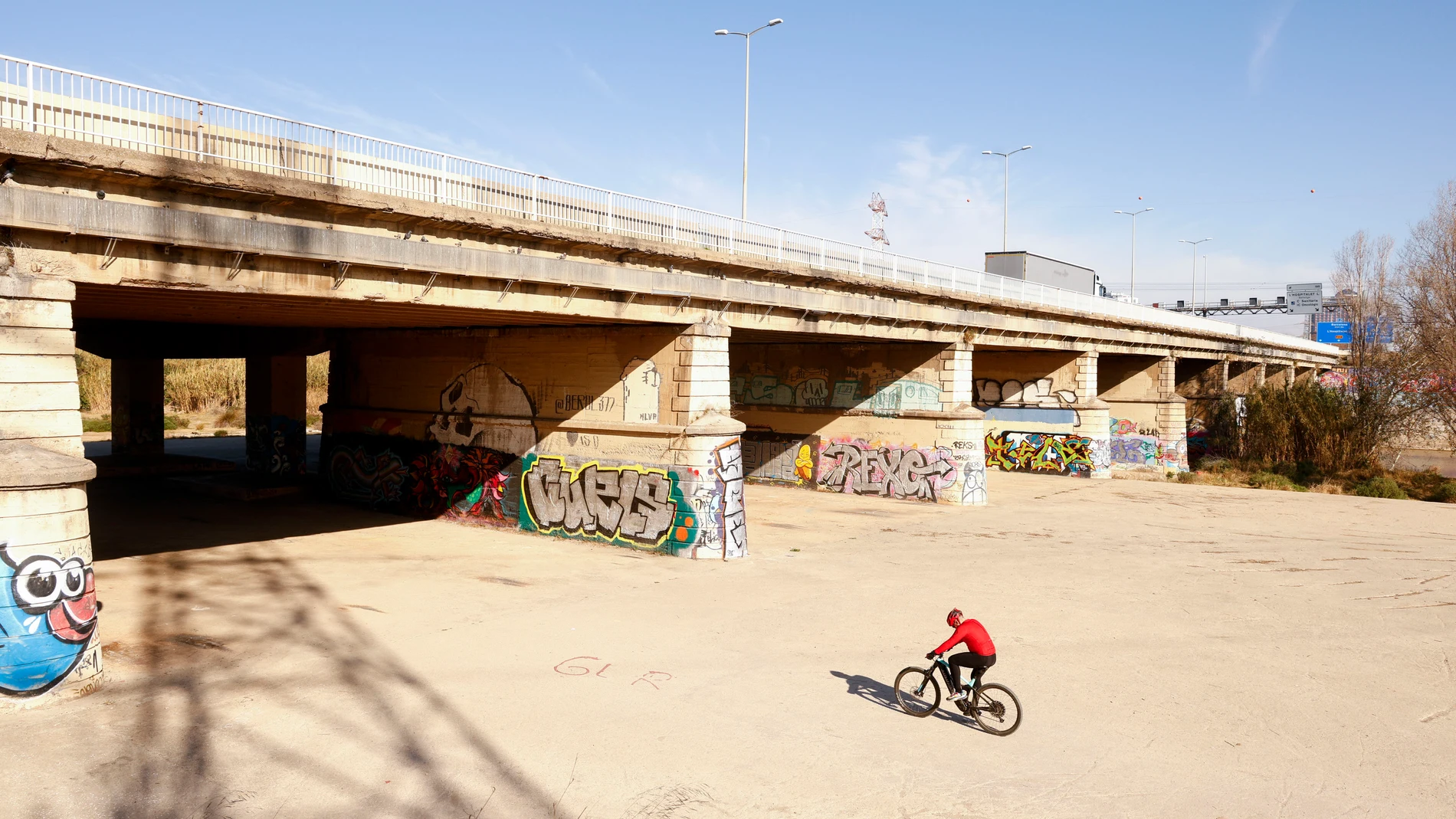 GRAFCAT9081. BARCELONA, 01/02/2024.- Una persona pasea en bicicleta por el margen urbanizado del rio Llobregat en El Prat del Llobregat, este jueves, cuando el Govern de la Generalitat ha declarado la emergencia por sequía, una situación sin precedentes, que tendrá efecto a partir de mañana viernes, y que afectará a 6 millones de catalanes del áreas de Barcelona y Girona, cuyo consumo quedará limitado a un máximo de 200 litros por habitante y día. EFE/Quique García