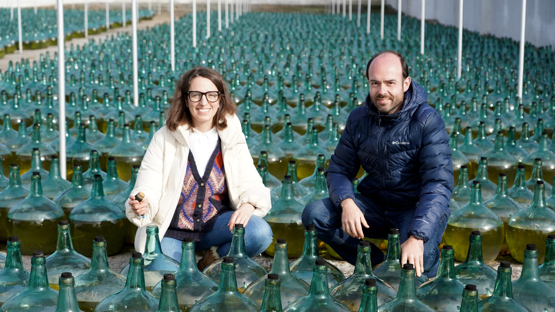 La responsable de Comunicación de Bodegas Hijos de Alberto Gutiérrez, Ángeles Jiménez, y el export manager, Mariano de Juan, junto a las damajuanas de los 'vinos generosos', en Serrada (Valladolid)