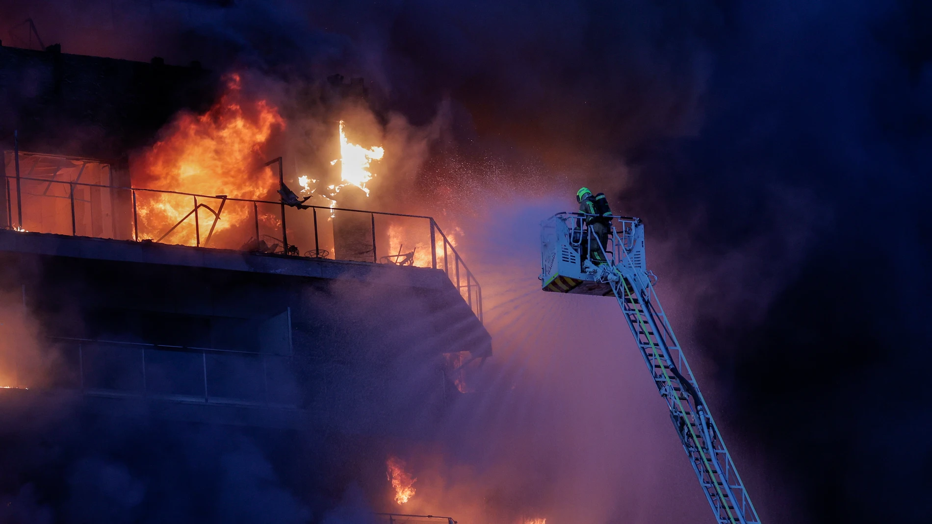 GRAFCVA8504. VALENCIA, 22/02/2024.- Bomberos trabajan en el incendio declarado sobre las cinco y media de esta tarde en un quinto piso de un edificio de viviendas de València que ha afectado totalmente al inmueble y se ha propagado a otro anexo, y los bomberos intentan aún rescatar a vecinos desde los balcones. EFE/Manuel Bruque