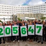 Un grupo de militantes socialistas portan carteles con la cifra 205.674, que corresponde a los sevillanos en listas de espera