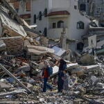 Una madre camina con sus hijos entre los escombros del campo de refugiados de Al Nuseirat, en el centro de Gaza