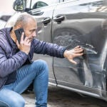 Un hombre observa un rasguño en la carrocería de su coche