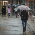 Varias personas pasean bajo la lluvia por el centro de Sevilla