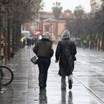Dos personas pasean por la calle San Fernando de Sevilla bajo la lluvia