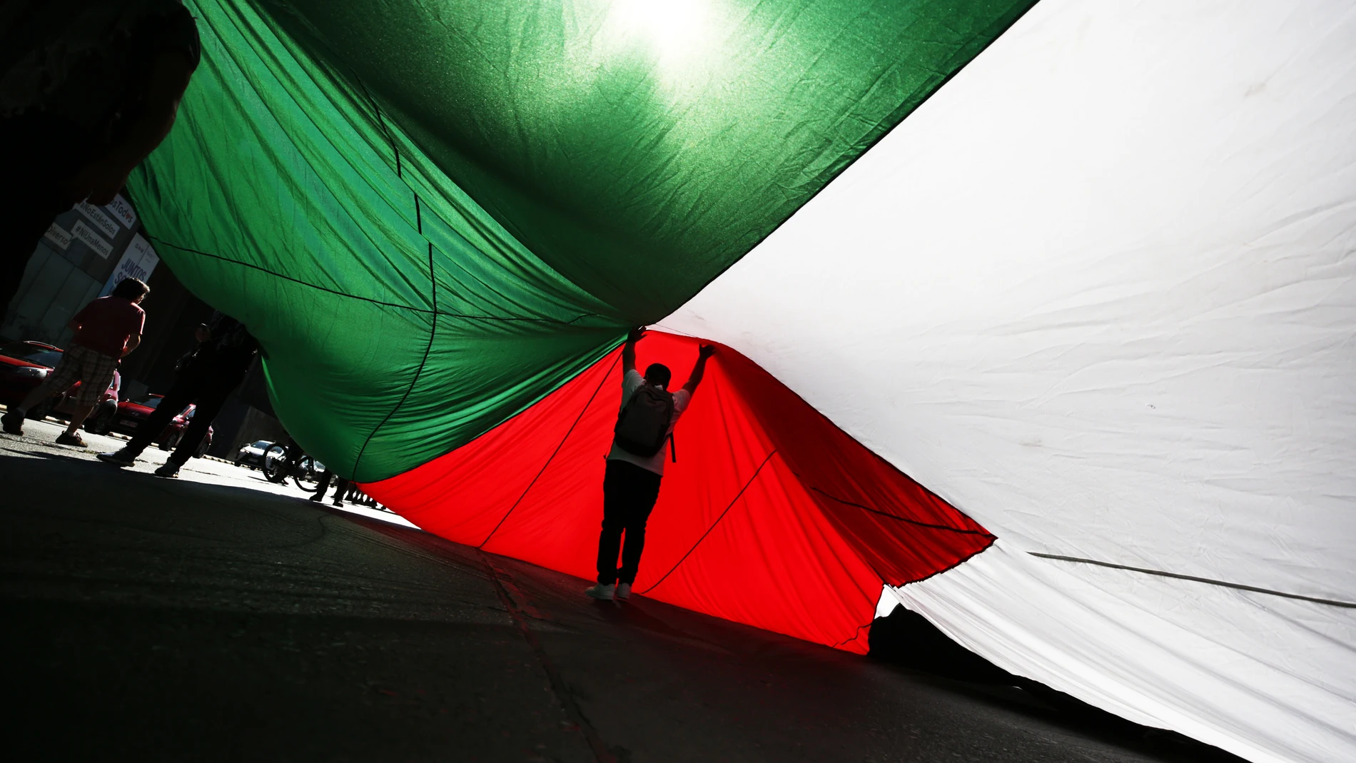 AME9513. SANTIAGO (CHILE), 17/03/2024.- Un hombre camina bajo una bandera gigante de Palestina durante una marcha en solidaridad este domingo, en Santiago (Chile). Ciudadanos marcharon por las calles de Santiago exigiendo un alto al fuego en Palestina. EFE/ Elvis González