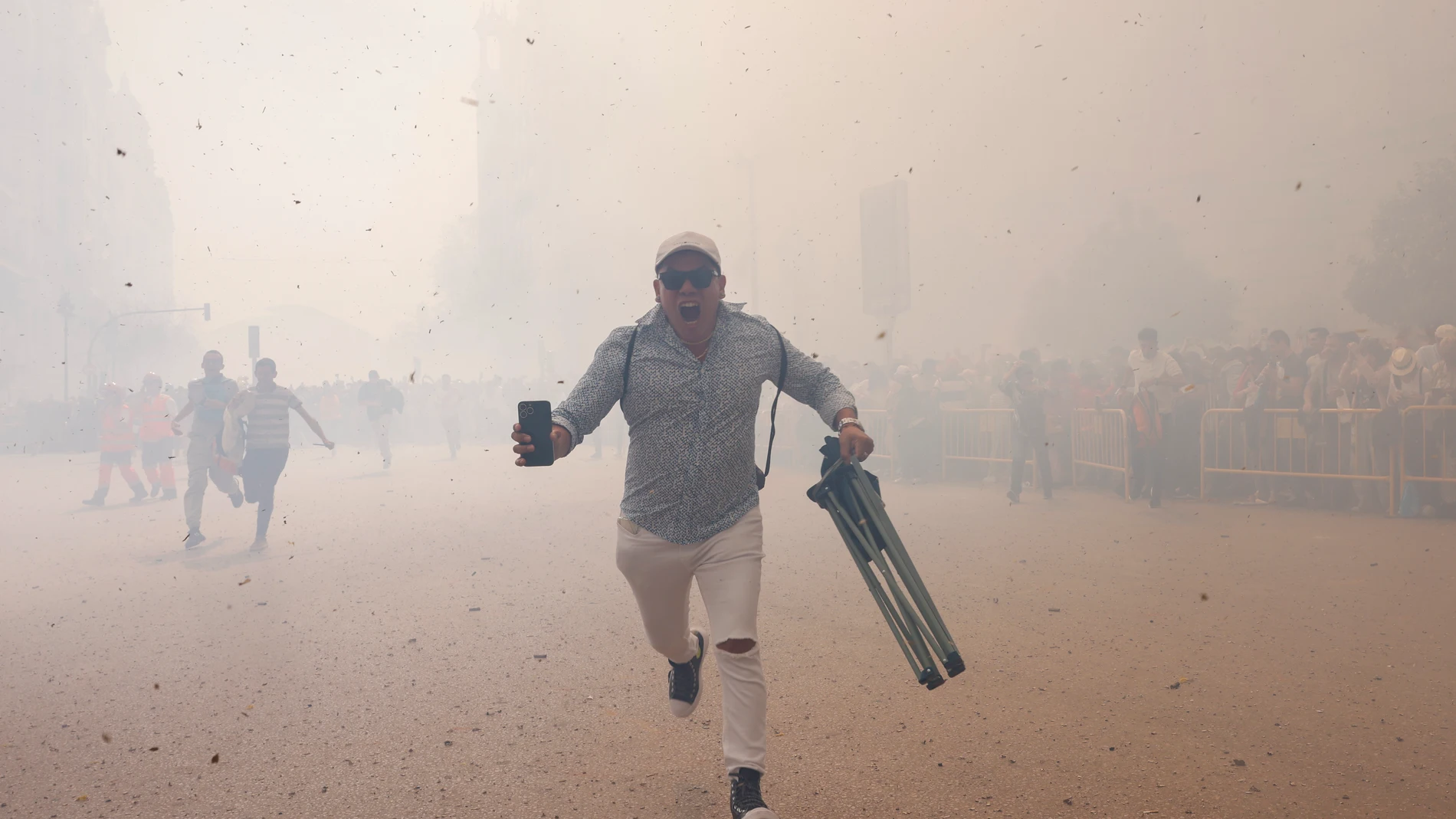 -FOTODELDÍA- GRAFCVA9351. VALENCIA, 18/03/2024.- Un espectador corre entre el humo al finalizar la penúltima mascletà Mascletà de las Fallas 2024 en la Plaza del Ayuntamiento a cargo de Pirotècnia Valenciana, de Llanera de Ranes (Valencia). EFE/Ana Escobar