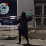 Imagen de los encapuchados arrojando pintura a la sedel del PP. 
