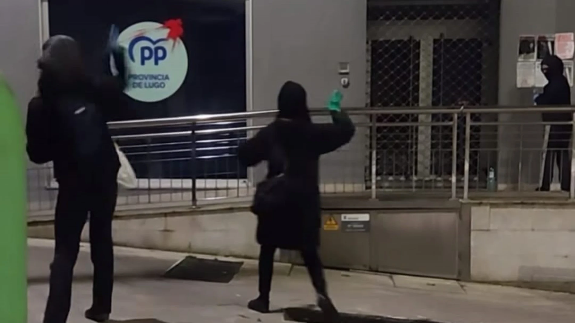 Imagen de los encapuchados arrojando pintura a la sedel del PP.