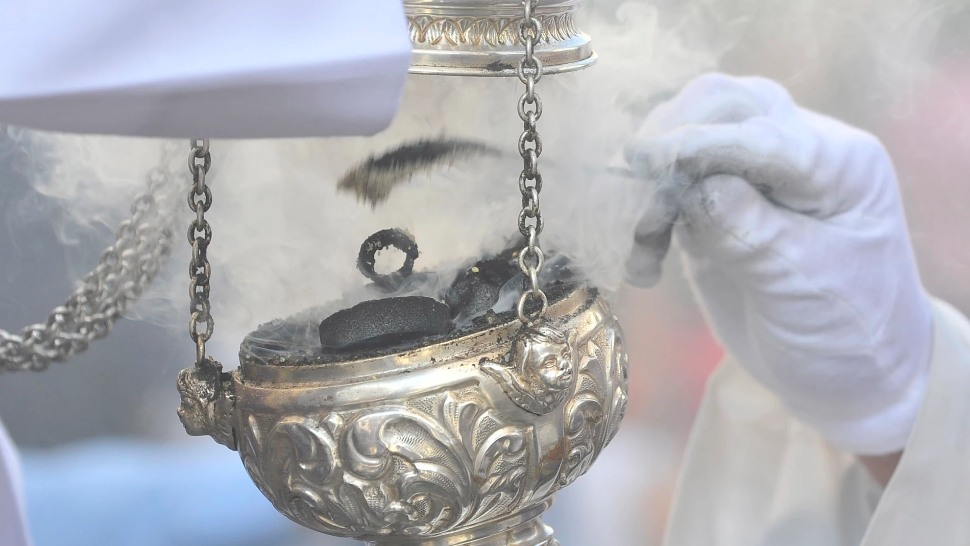 Un acólito recarga un incensario durante un procesión