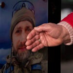 Un familiar toca la fotografía de un familiar muerto durante la ocupación rusa de Bucha