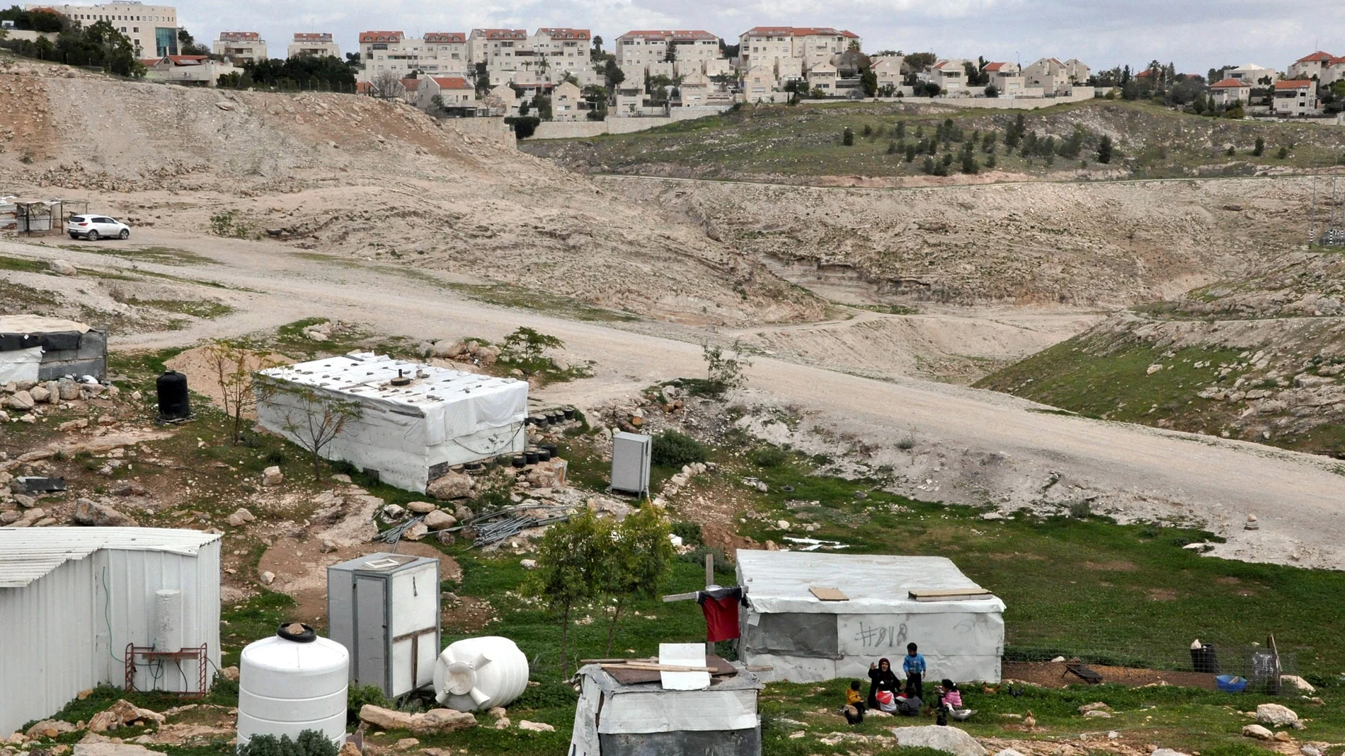 Ma'ale Adumim, back ground, an urban Israeli settlement , is near village, front, in the West Bank on March 7, 2024.