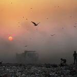 FILE- In this Oct. 17, 2014, file photo, a thick blanket of smoke is seen against the setting sun as young ragpickers search for reusable material at a garbage dump in New Delhi, India. India launched the Air Quality Index Friday to measure air quality across the nation that is home to some of the most polluted cities in the world. A groundbreaking agreement struck Wednesday, Nov. 12, 2014, by the United States and China puts the world's two worst polluters on a faster track to curbing the heat-trapping gases blamed for global warming. (AP Photo/Altaf Qadri, File)