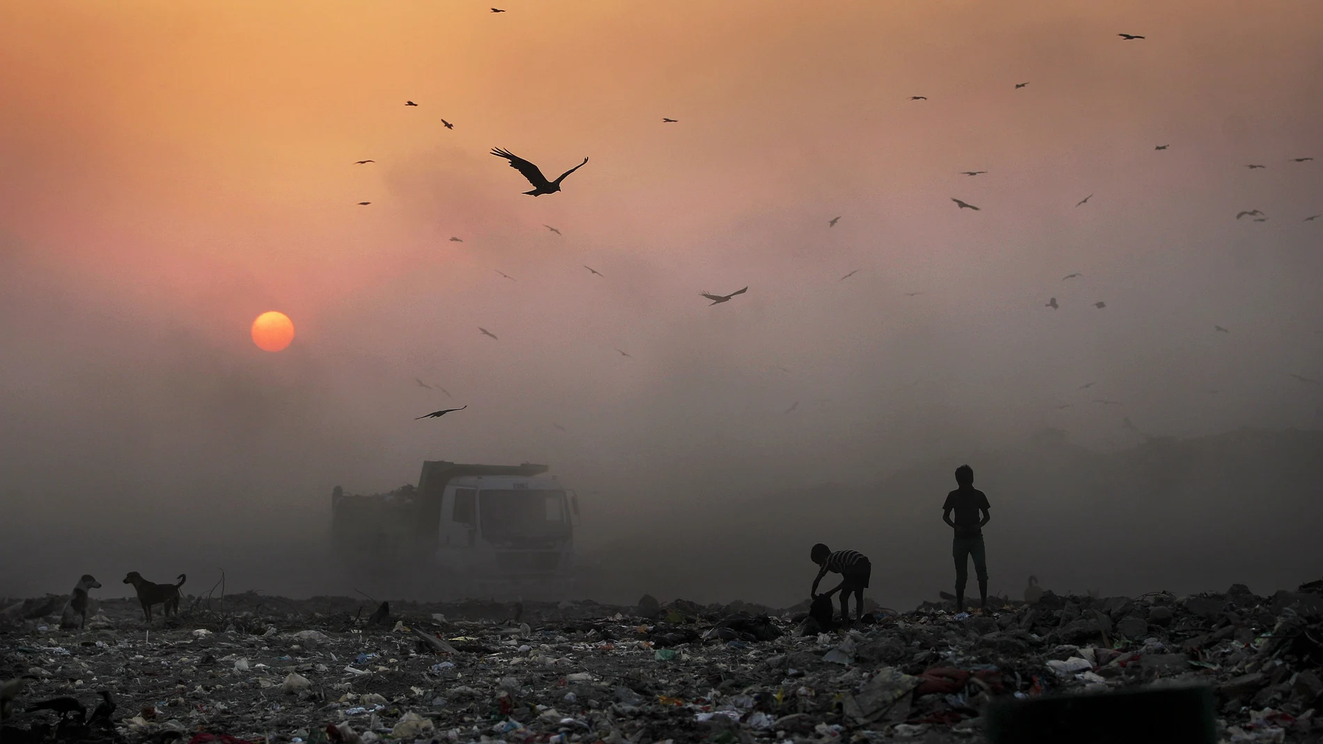 FILE- In this Oct. 17, 2014, file photo, a thick blanket of smoke is seen against the setting sun as young ragpickers search for reusable material at a garbage dump in New Delhi, India. India launched the Air Quality Index Friday to measure air quality across the nation that is home to some of the most polluted cities in the world. A groundbreaking agreement struck Wednesday, Nov. 12, 2014, by the United States and China puts the world's two worst polluters on a faster track to curbing the heat-trapping gases blamed for global warming. (AP Photo/Altaf Qadri, File)