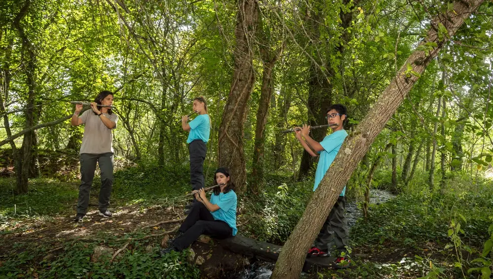 Jóvenes de la Música del reciclaje tocando los instrumentos en un paisaje natural