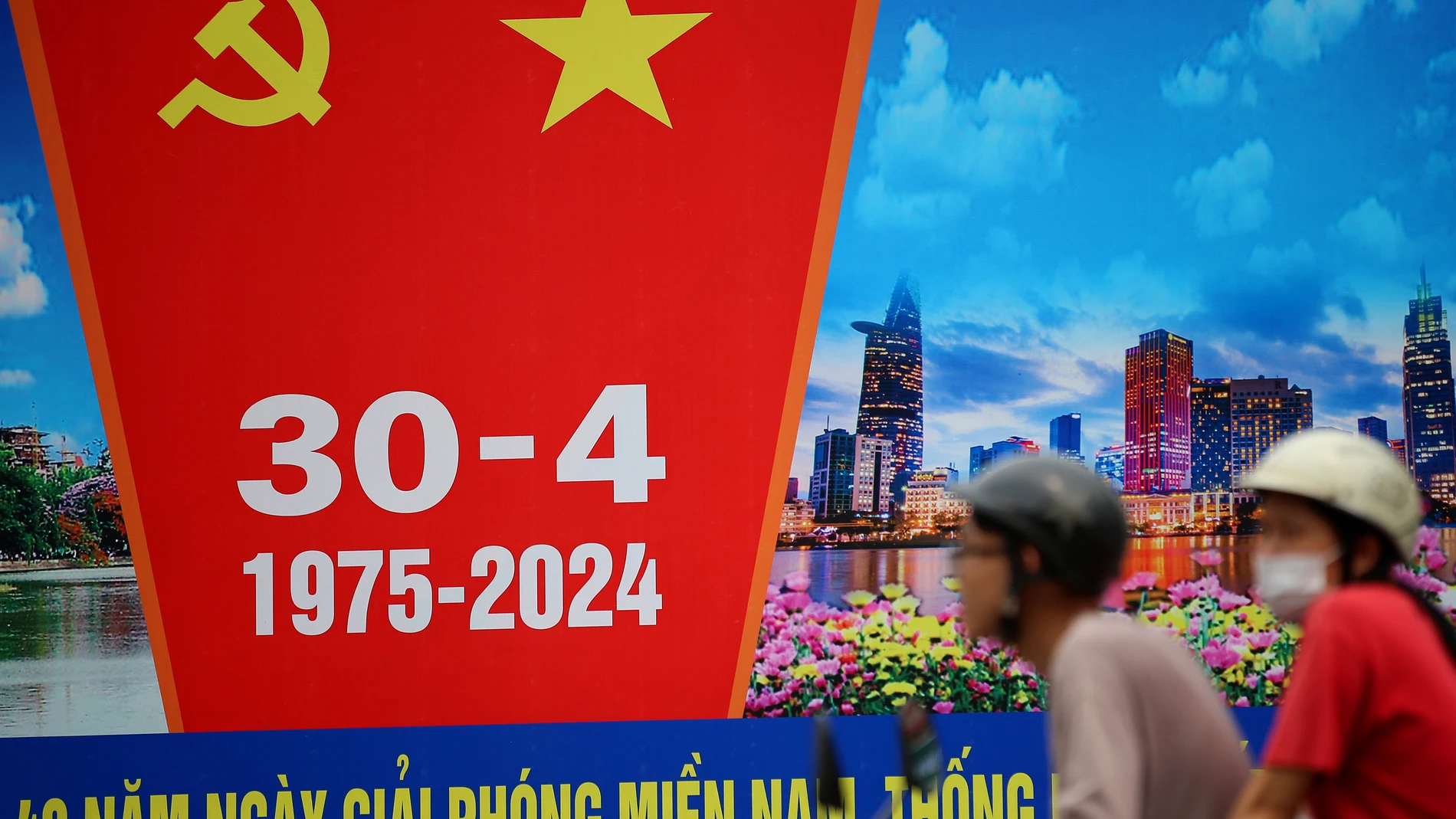 Ha Noi (Viet Nam), 29/04/2024.- A man rides past a billboard featuring an advertisement for Reunification Day or Liberation Day, which marked the end the Vietnam War in 1975, in Hanoi, Vietnam, 29 April 2024. Vietnamese Reunification Day is observed annually on 30 April. EFE/EPA/LUONG THAI LINH