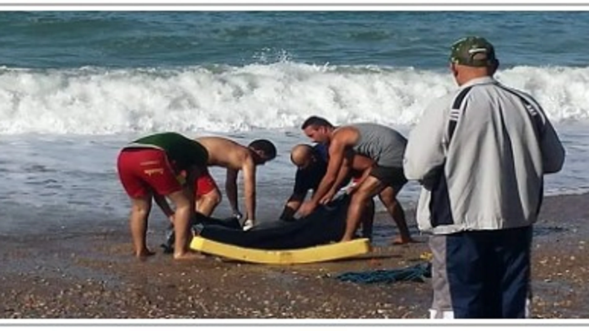 Varias personas recoger el cadáver de un inmigrante ahogado en el mar
