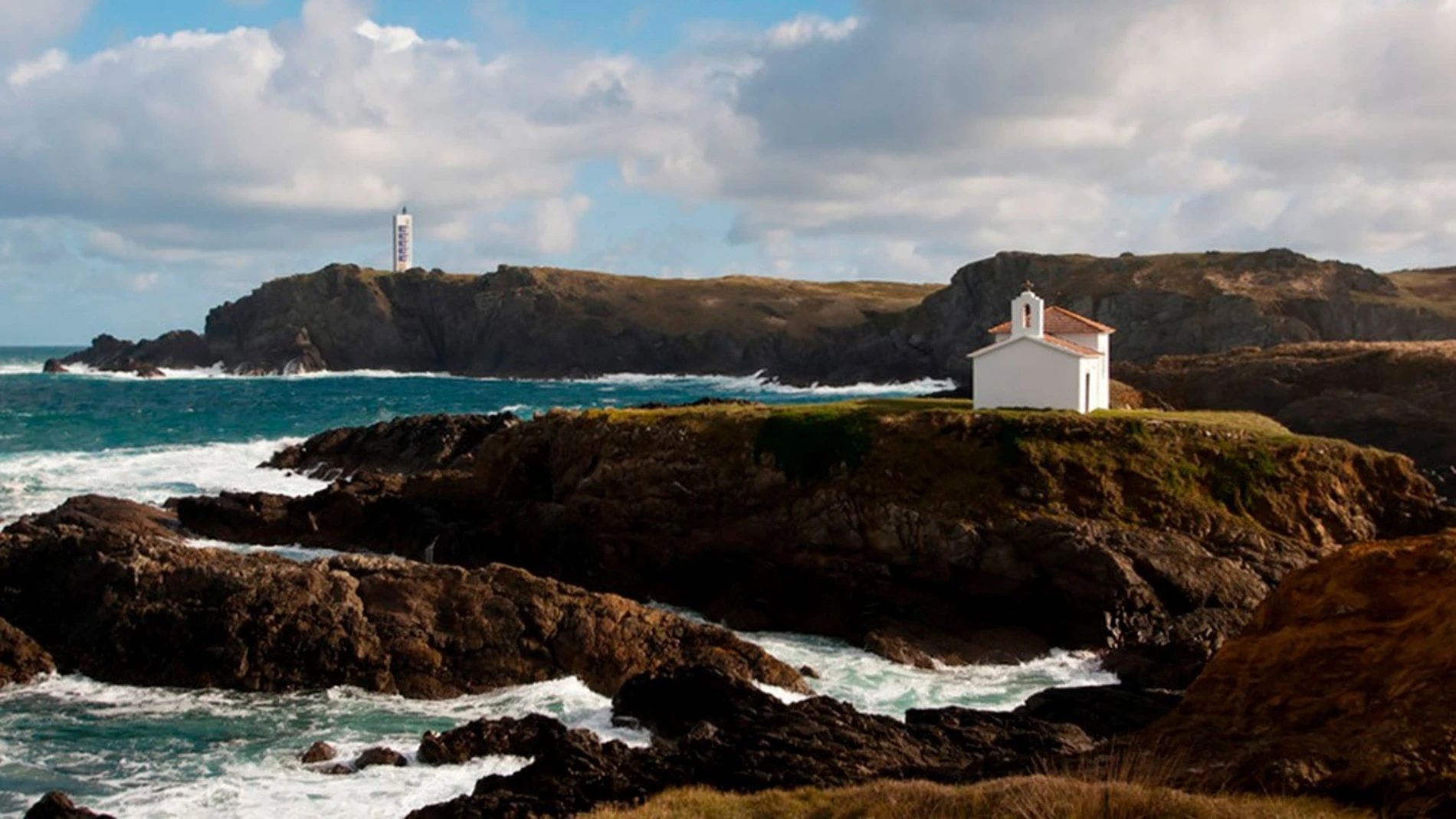 La ermita de la Virxe do Porto con el Faro de Punta Frouxeira, al fondo.